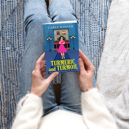 woman in jeans reading a paperback of  turmeric and turmoil by carly winter
